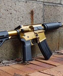 Custom gold AR-15 rifle against brick wall